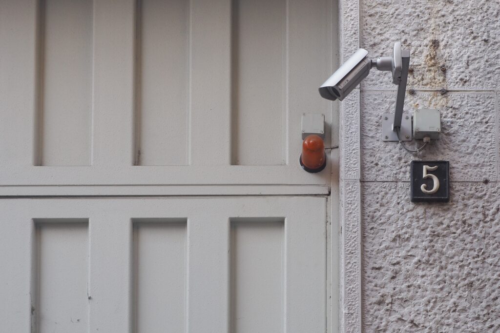 Gray security camera near a white wooden door