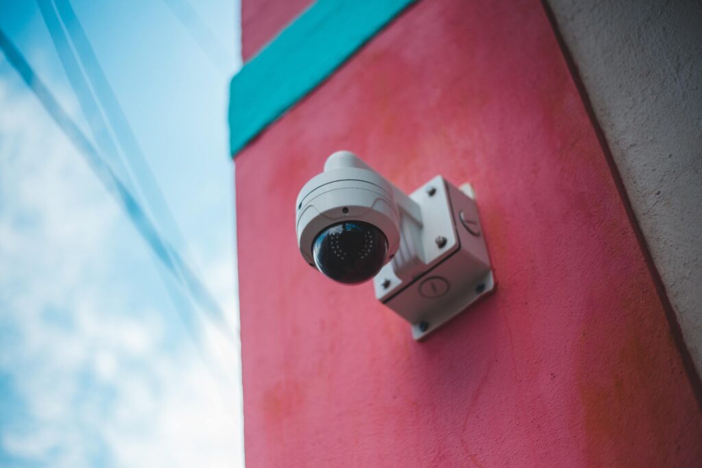 A white round security camera on a pink wall