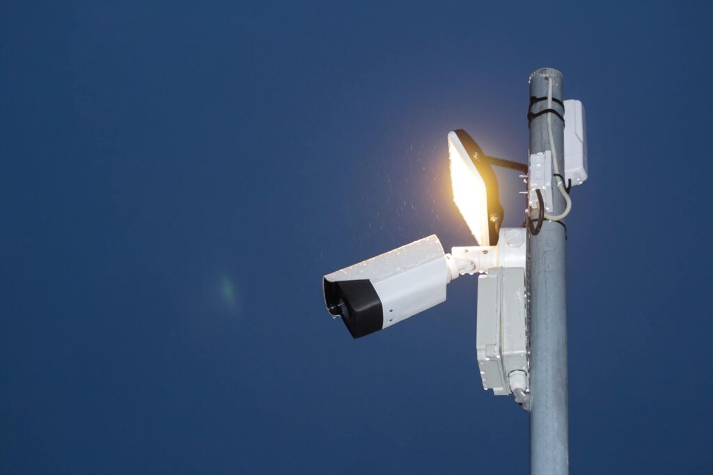 Black and white security camera with street light on a pol